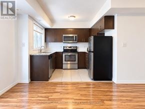 Oakville (Ro River Oaks) townhouse for rent - A kitchen with a black fridge and stove top oven.