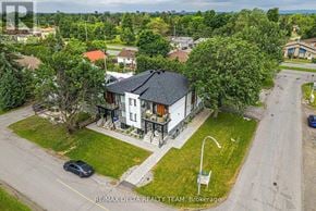 Ottawa apartment for rent - A house with a black roof is surrounded by greenery and a car is parked in front of it.