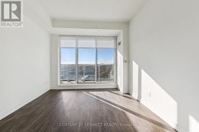Richmond Hill condo for rent - A room with wooden floors and a large window overlooking a cityscape.