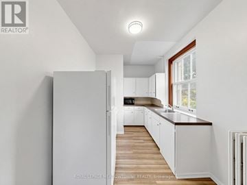 Halton Hills (Georgetown) multi-family for rent - A white kitchen with a refrigerator and wooden floors.
