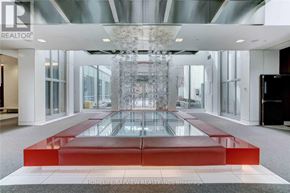 Toronto (North St. James Town) condo for rent - A large glass table with a red base is in the center of a spacious room.
