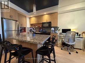 Toronto (North St. James Town) condo for rent - A kitchen with a granite countertop and black barstools.