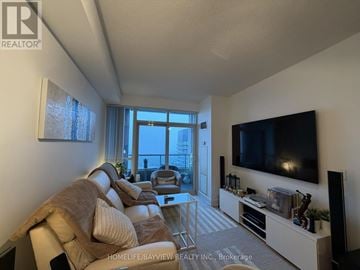 Toronto (North St. James Town) condo for rent - A living room with a couch, a chair, a television and a window.