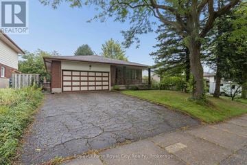 Guelph (Kortright West) apartment for rent - A driveway leads to a garage with a tree on the right.