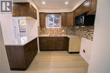 Kitchener apartment for rent - A kitchen with wooden cabinets and a tiled backsplash.