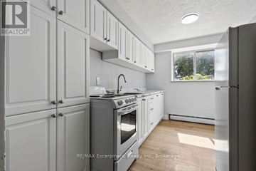 Burlington (Brant) multi-family for rent - A kitchen with white cabinets and a stove top oven.