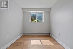 Burlington (Brant) multi-family for rent - A room with a window showing a view of trees and a wall with a REALTOR® logo.