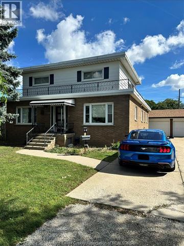Windsor apartment for rent - A blue car is parked in front of a two-story house.