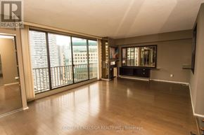 Toronto (Waterfront Communities) condo for rent - A spacious room with wooden floors and large windows overlooking a cityscape.