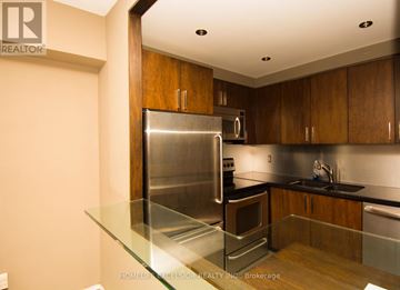 Toronto (Waterfront Communities) condo for rent - A modern kitchen with wooden cabinets and stainless steel appliances.