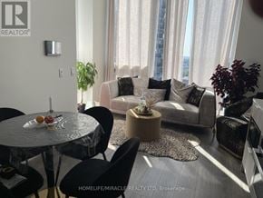 Mississauga (Port Credit) condo for rent - A living room with a glass table and a couch with pillows.