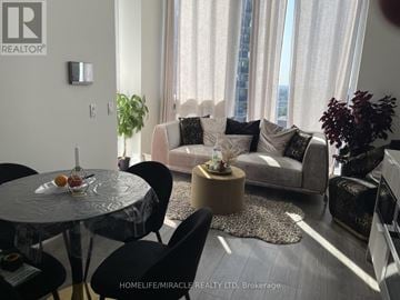 Mississauga (Port Credit) condo for rent - A living room with a glass table and a couch with pillows.