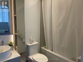 Mississauga (Port Credit) condo for rent - A white bathroom with a toilet, sink, and shower curtain.