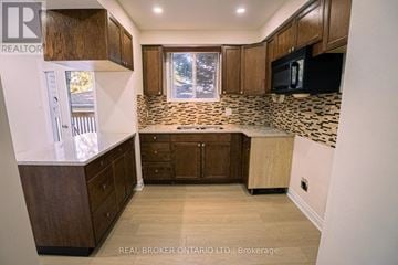 Kitchener apartment for rent - A kitchen with wooden cabinets and a tiled backsplash.