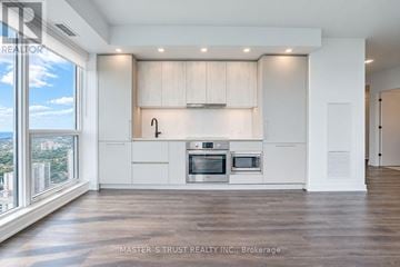 Toronto (North St. James Town) condo for rent - A spacious kitchen with white cabinets and a large window overlooking the city.