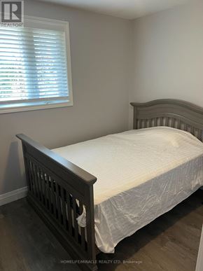 Bradford West Gwillimbury (Bradford) apartment for rent - A bed with a white sheet and a wooden headboard.