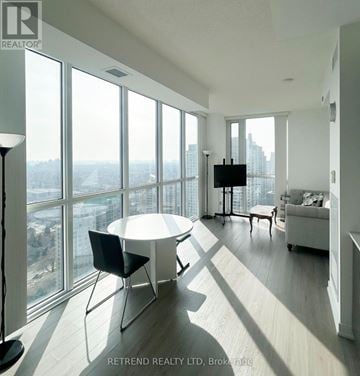 Toronto (Willowdale West) condo for rent - A living room with a large window overlooking a cityscape.