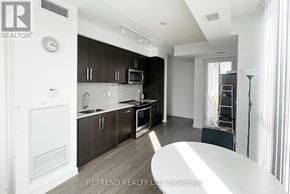 Toronto (Willowdale West) condo for rent - A kitchen with dark brown cabinets and a white refrigerator.