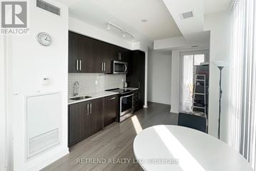 Toronto (Willowdale West) condo for rent - A kitchen with dark brown cabinets and a white refrigerator.