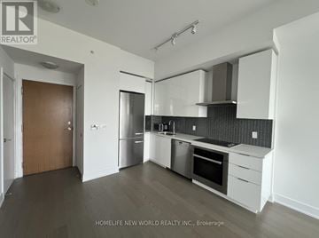 Toronto (Mimico) condo for rent - A kitchen with white cabinets and a black backsplash.