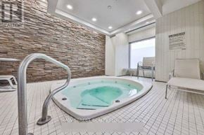 Toronto (Bendale) condo for rent - A hot tub sits in the middle of a tiled room with a stone wall.