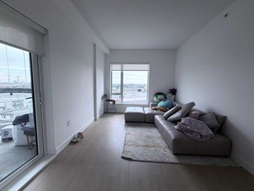 Vancouver apartment for rent - A living room with a grey couch and a large window.