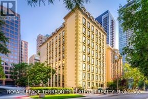 Toronto (Church-Yonge Corridor) condo for rent - A large, beige building with many windows is surrounded by trees and other buildings.