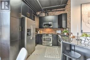 London North (North E) condo for rent - A modern kitchen with a brick wall and stainless steel appliances.