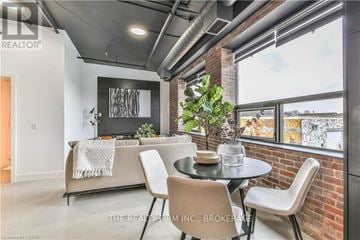 London North (North E) condo for rent - A modern living room with a brick wall and a dining table set for two.