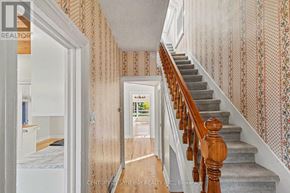 Ottawa apartment for rent - A hallway with a staircase and a doorway leading to a bedroom.