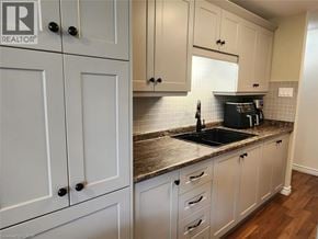 Kitchener condo for rent - A kitchen with white cabinets and a granite countertop.