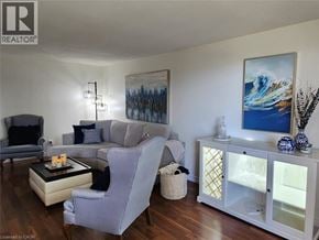 Kitchener condo for rent - A living room with a grey couch, a white chair, and a painting on the wall.