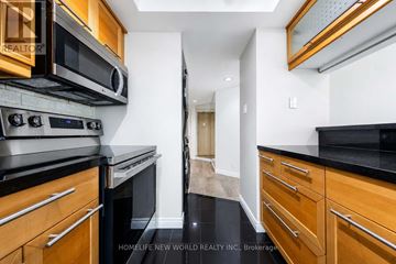 Toronto (Waterfront Communities) condo for rent - A modern kitchen with wooden cabinets and black countertops.
