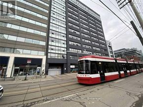 Toronto (Niagara) condo for rent - A red and white tram is on a city street in front of a large building.