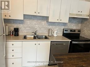 Toronto (Niagara) condo for rent - A kitchen with white cabinets and a stone backsplash.
