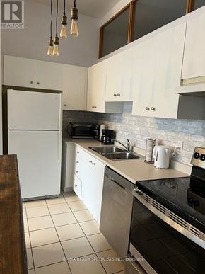 Toronto (Niagara) condo for rent - A kitchen with white cabinets and a white refrigerator.