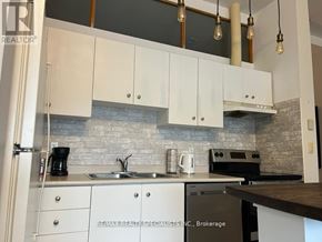 Toronto (Niagara) condo for rent - A kitchen with white cabinets and a brick backsplash.