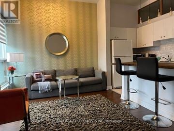 Toronto (Niagara) condo for rent - A living room with a grey couch and a round mirror on the wall.