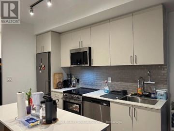 Oakville (Jm Joshua Meadows) condo for rent - A kitchen with white cabinets and a black refrigerator.