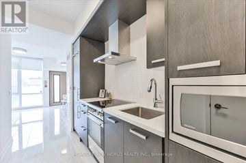 Toronto (Waterfront Communities) townhouse for rent - A modern kitchen with stainless steel appliances and white countertops.