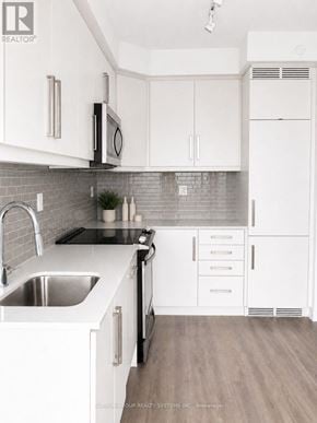 Toronto (Willowdale West) condo for rent - A kitchen with white cabinets and a grey backsplash.