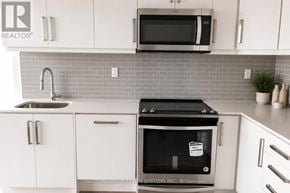 Toronto (Willowdale West) condo for rent - A modern kitchen with white cabinets and a black oven.