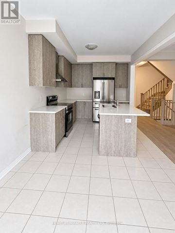 Cambridge apartment for rent - A modern kitchen with white tiled floors and a staircase in the background.