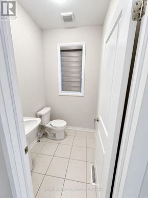 Cambridge apartment for rent - A white bathroom with a toilet, sink, and window.