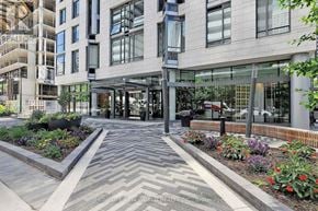 Toronto (Church-Yonge Corridor) condo for rent - A modern building with a glass entrance and a landscaped garden in front.