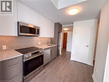 Kitchener condo for rent - A kitchen with a stove top oven and microwave above it.