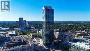 Kitchener condo for rent - A cityscape with a tall building in the foreground and a clear blue sky above.