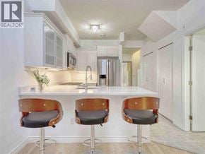 Vancouver apartment for rent - A modern kitchen with white cabinets and a bar area with two stools.