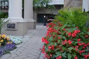 Toronto (Bayview Village) condo for rent - A flower bed with red flowers in front of a building.
