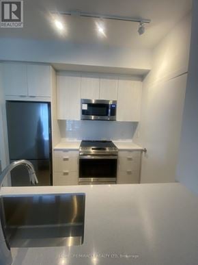 Mississauga (City Centre) condo for rent - A modern kitchen with stainless steel appliances and white cabinets.